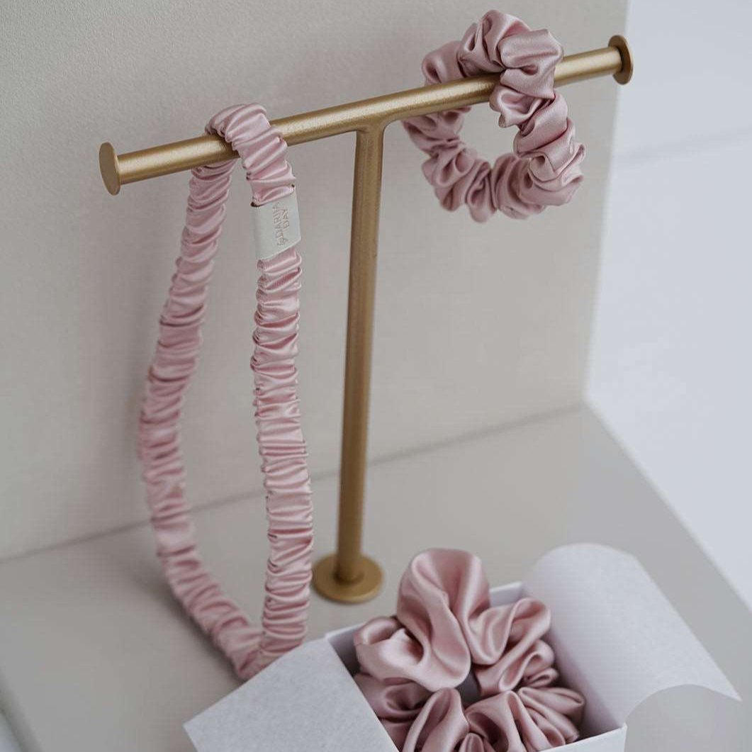 Pink Elegant display of blush pink silk headband and scrunchie by Dariia Day, perfect for adding a touch of luxury to any hair care routine
