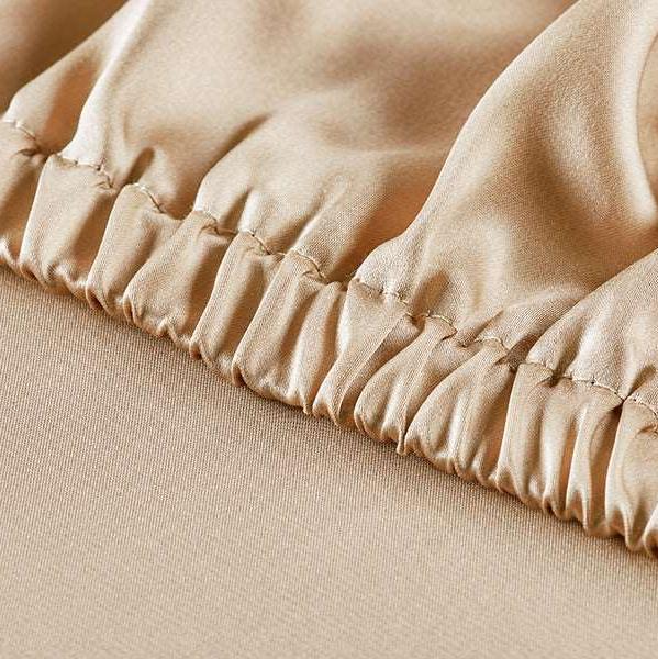 Beige Detailed view of the high-quality craftsmanship of a French beige silk fitted sheet with an elastic hem, providing a secure and snug fit for any mattress.