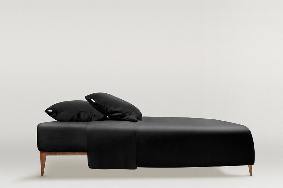 Black Minimalistic full silk bedding set in Midnight Black by Dariia Day, with neatly arranged pillows and sheets for a modern aesthetic.