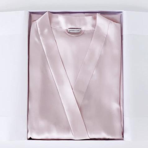 Pink Detailed close-up of a folded light blush pink silk robe with Dariia Day branding.