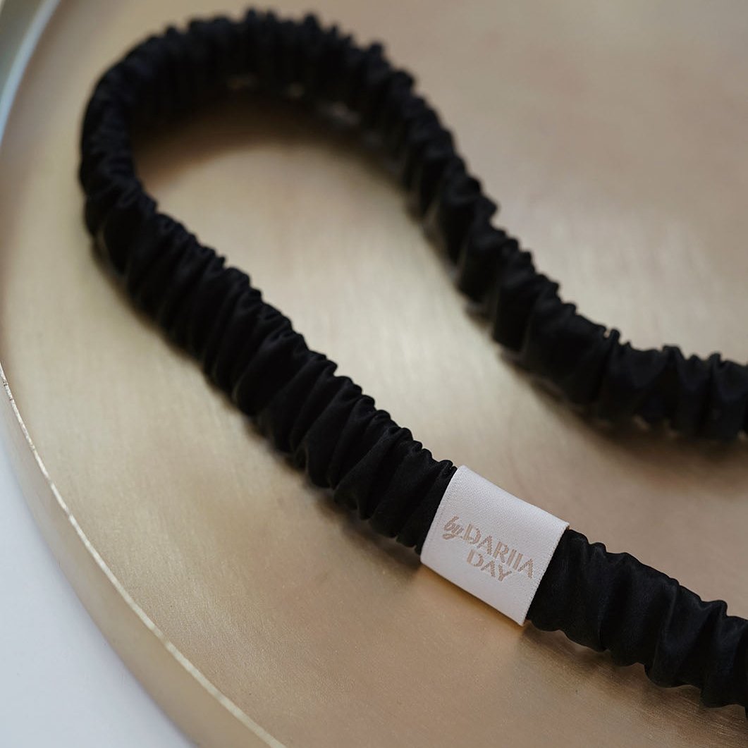 Black Midnight Black silk headband by Dariia Day elegantly placed on a gold tray, highlighting its luxurious texture.