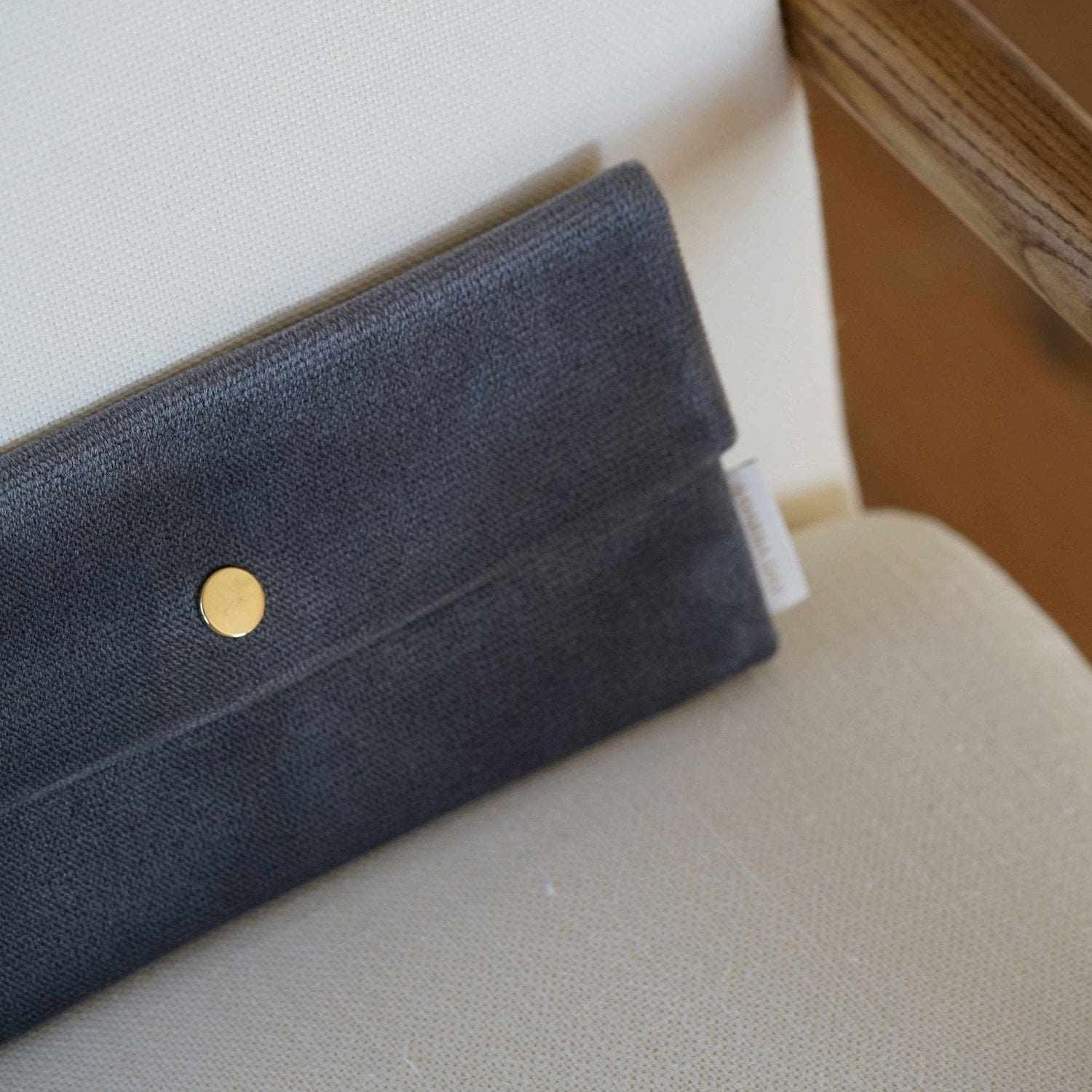 Moonstone Dariia Day Moonstone Velvet Pouch placed on a beige chair with a close-up view of its elegant gold button.