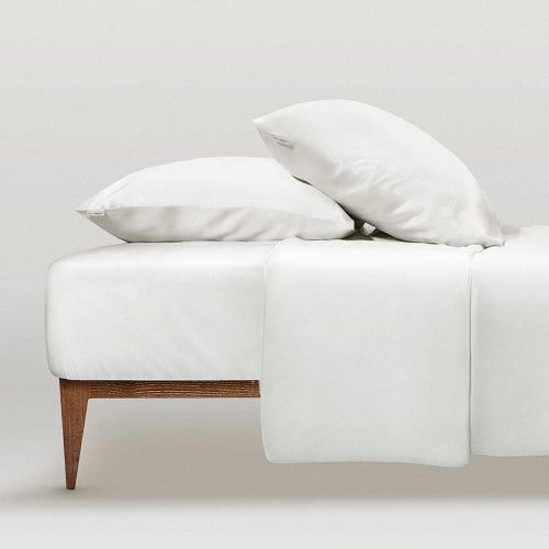 White legant white silk bedding set by Dariia Day, featuring pillowcases on a minimalist wooden bed frame.