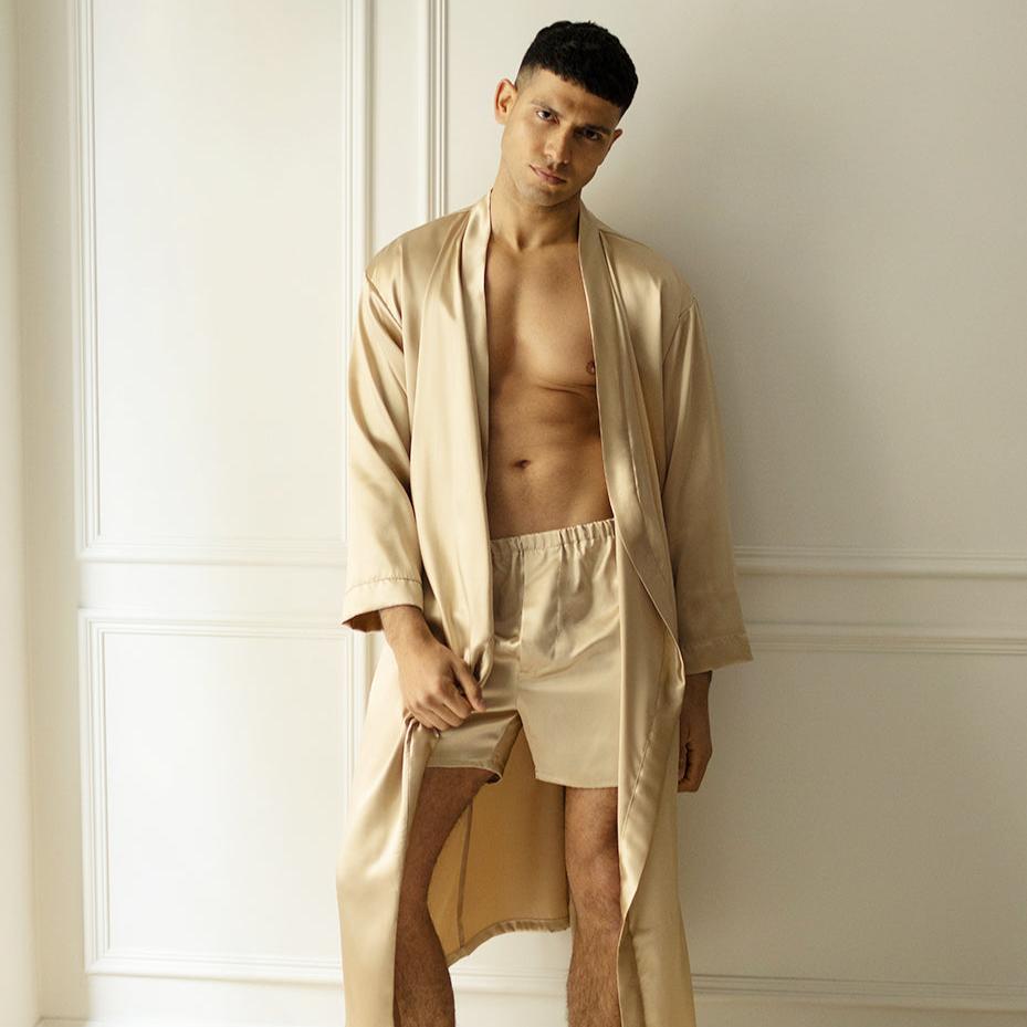 Beige Man wearing French beige silk boxers and a matching robe by Dariia Day, standing against a white wall.