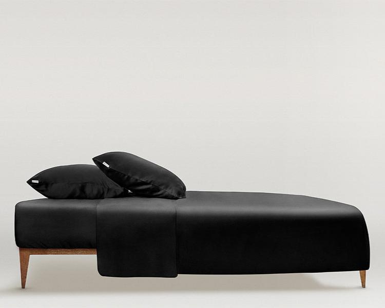 Black Luxurious bed styled with a midnight black silk duvet cover and matching pillows by Dariia Day, showcasing the smooth and elegant look of the high-quality fabric.