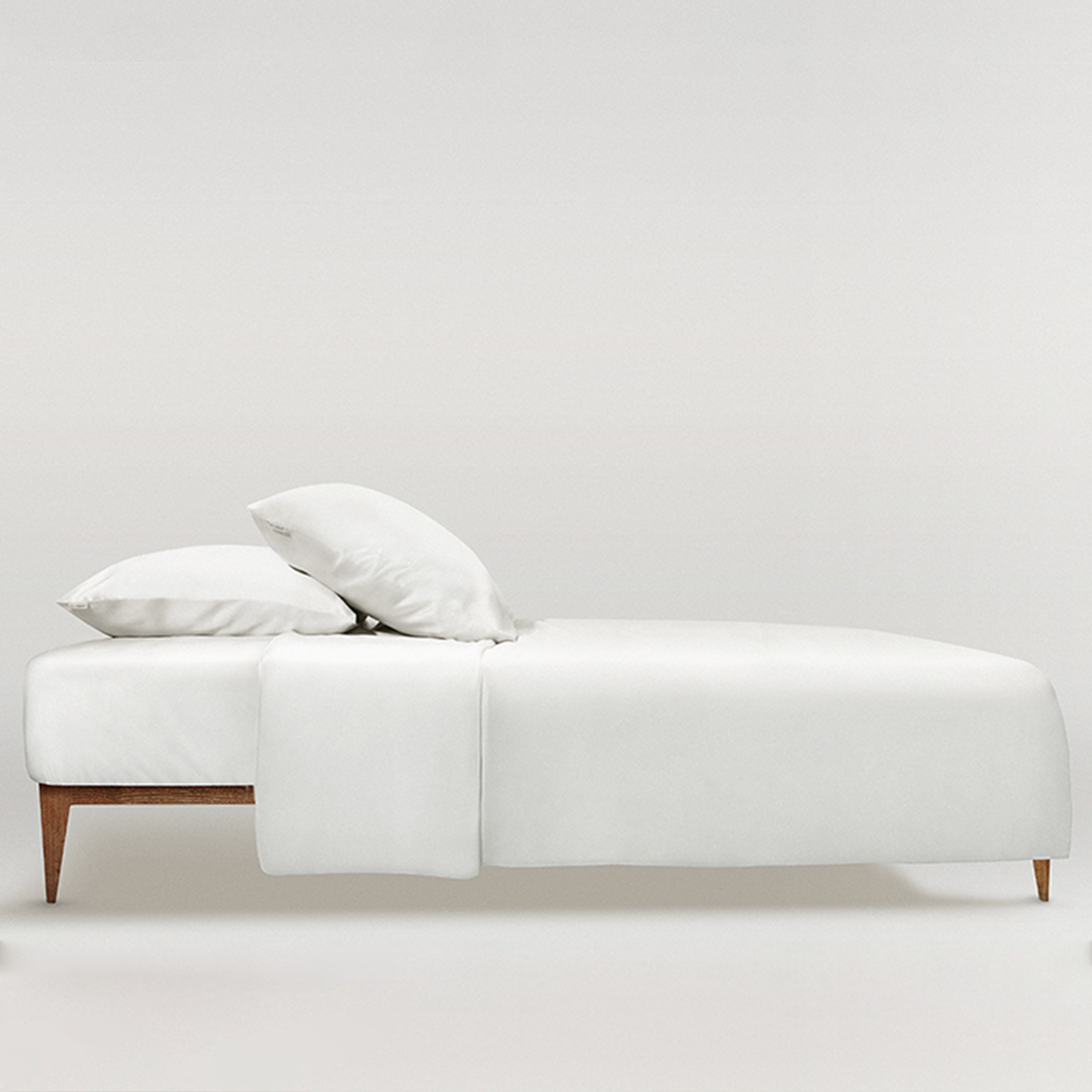 White Minimalist bedroom featuring a powder white Mulberry silk duvet cover and pillows by Dariia Day, highlighting the soft and smooth texture of the luxurious silk bedding.
