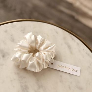 White Powder white silk scrunchie by Dariia Day displayed on a marble table, a luxurious hair accessory with a soft touch.