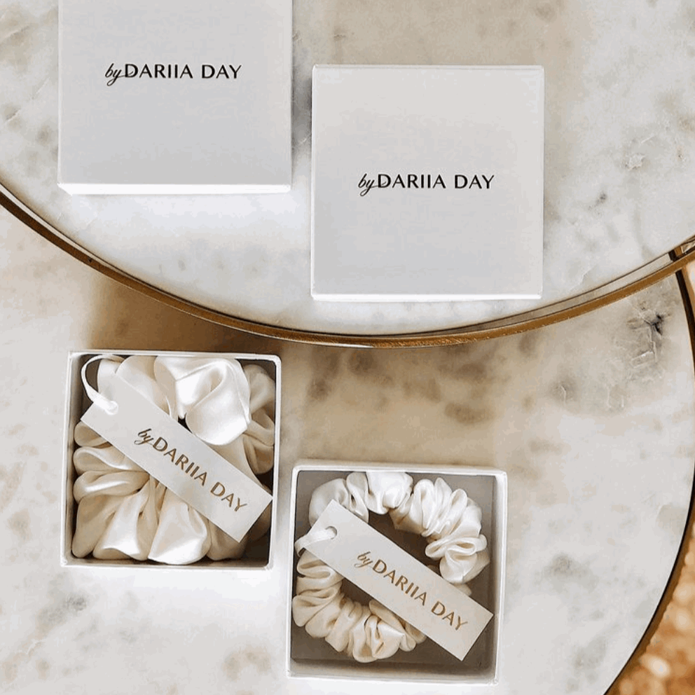 White Two powder white silk scrunchies by Dariia Day displayed in elegant gift boxes, a luxurious accessory for hair.