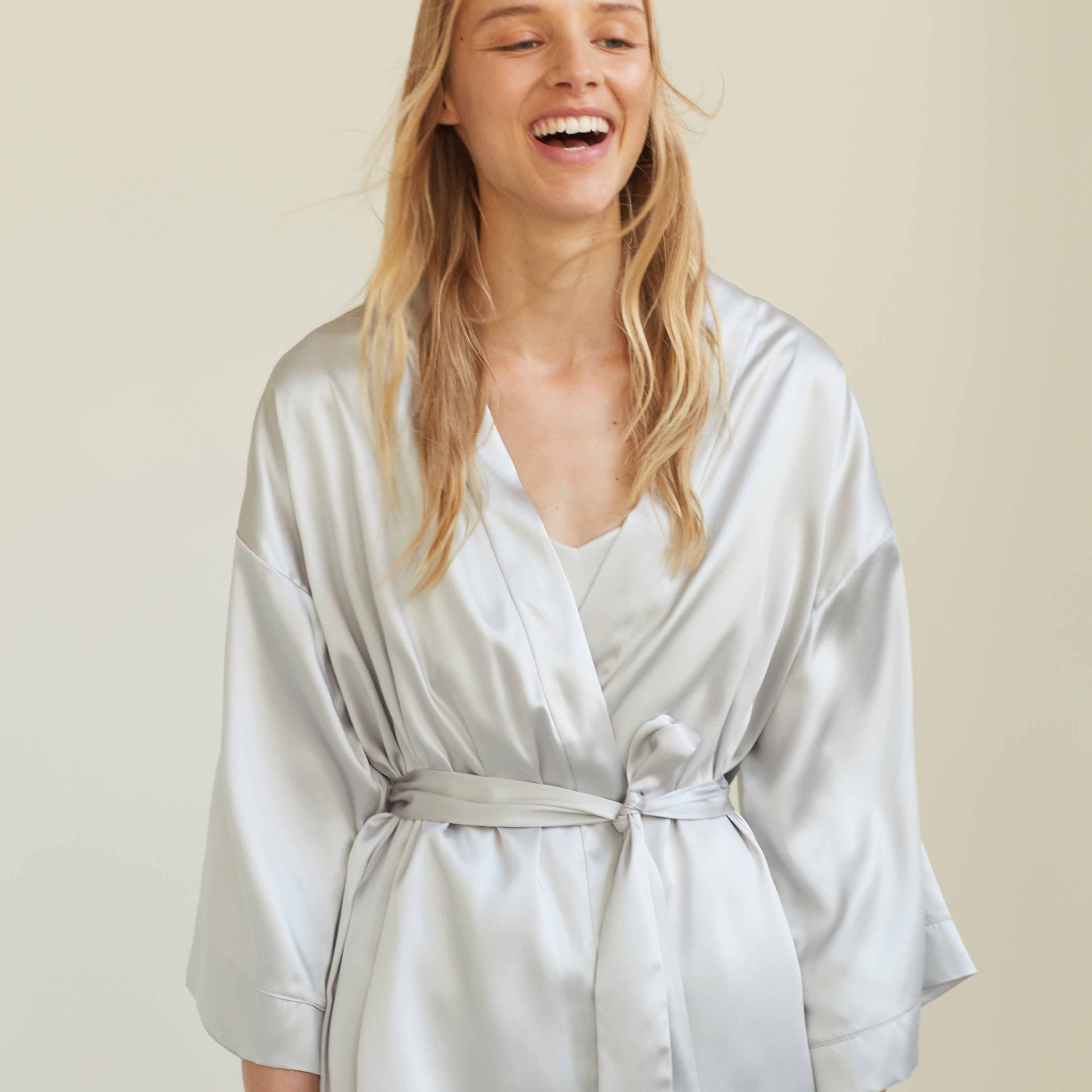 Grey Woman wearing the luxurious silver grey silk robe by Dariia Day, smiling and enjoying the comfortable, elegant fit.