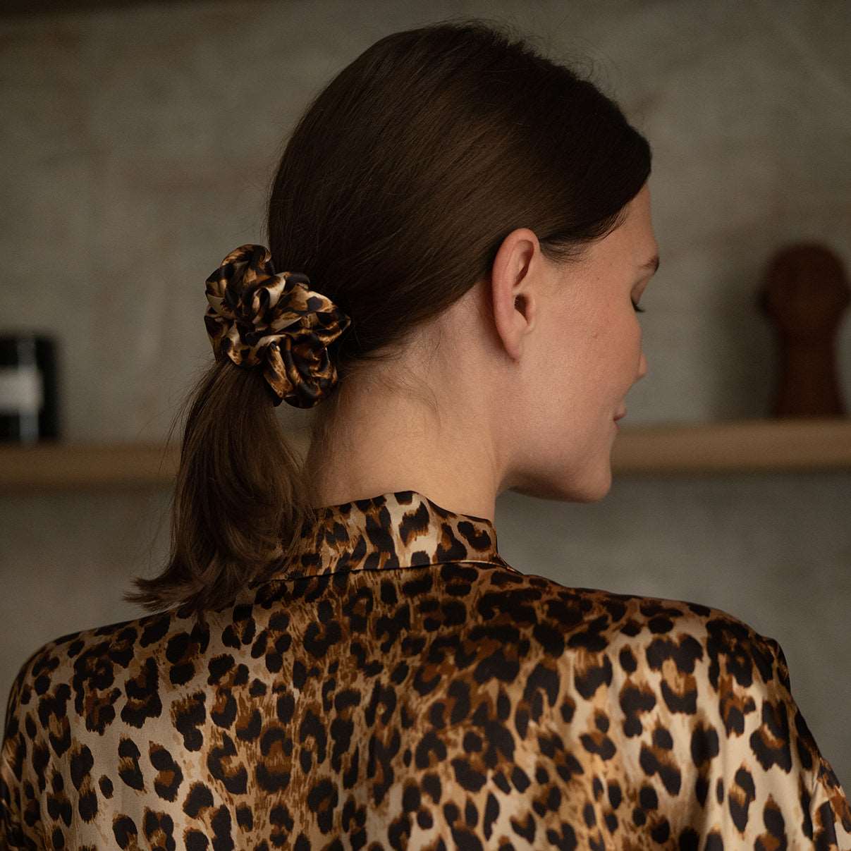 Leopard Back view of a woman wearing a leopard-print silk scrunchie and matching robe from the Daria Day Leopard collection, showcasing elegance and style.