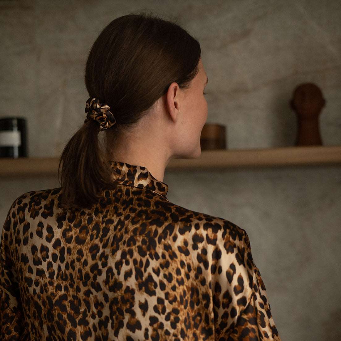Leopard Back view of a woman wearing a leopard-print silk scrunchie and matching robe from the Daria Day Leopard collection, showcasing elegance and style.
