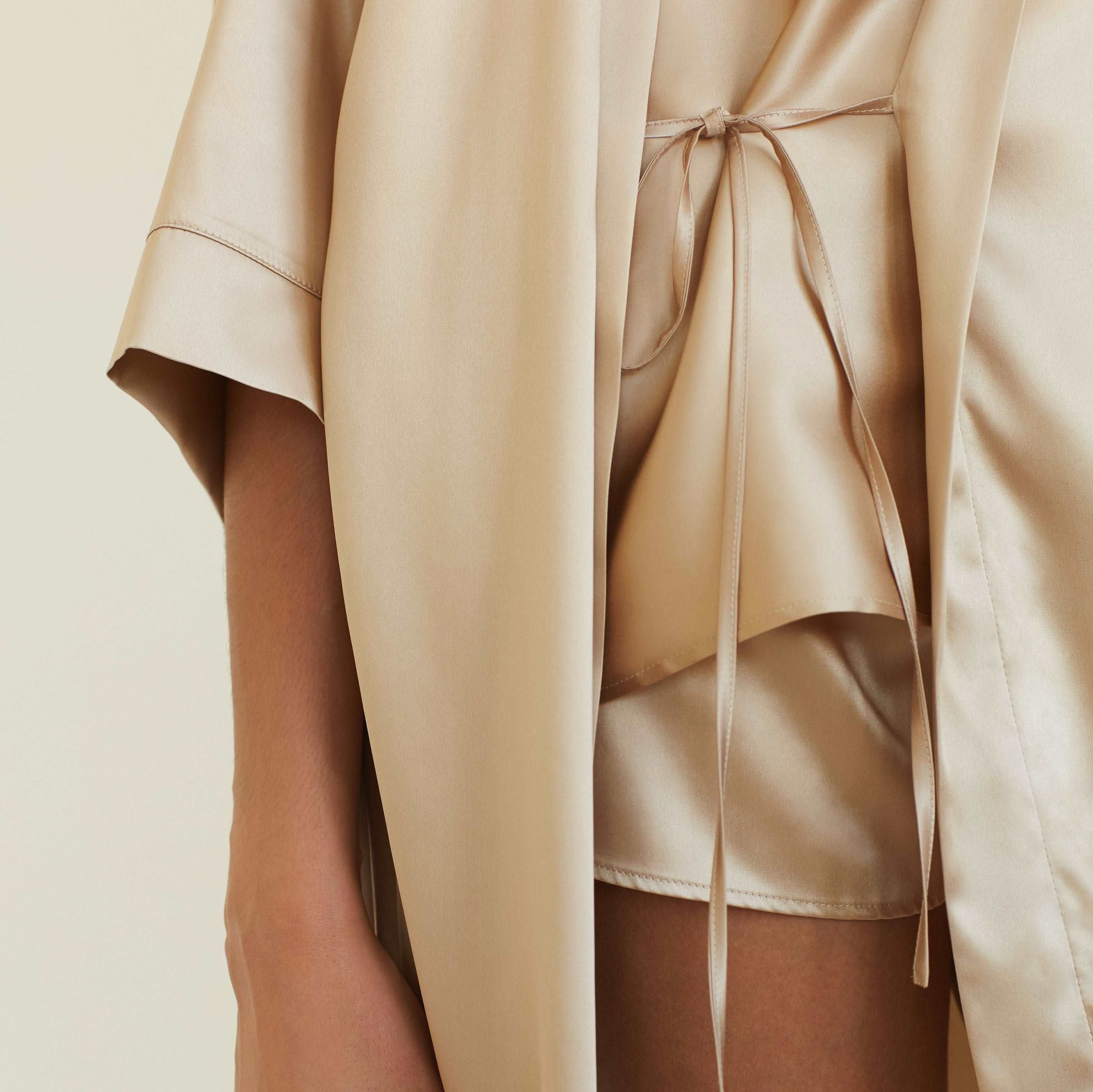 Close-up of the tie detail on the beige silk robe, showing the luxurious and soft fabric texture.