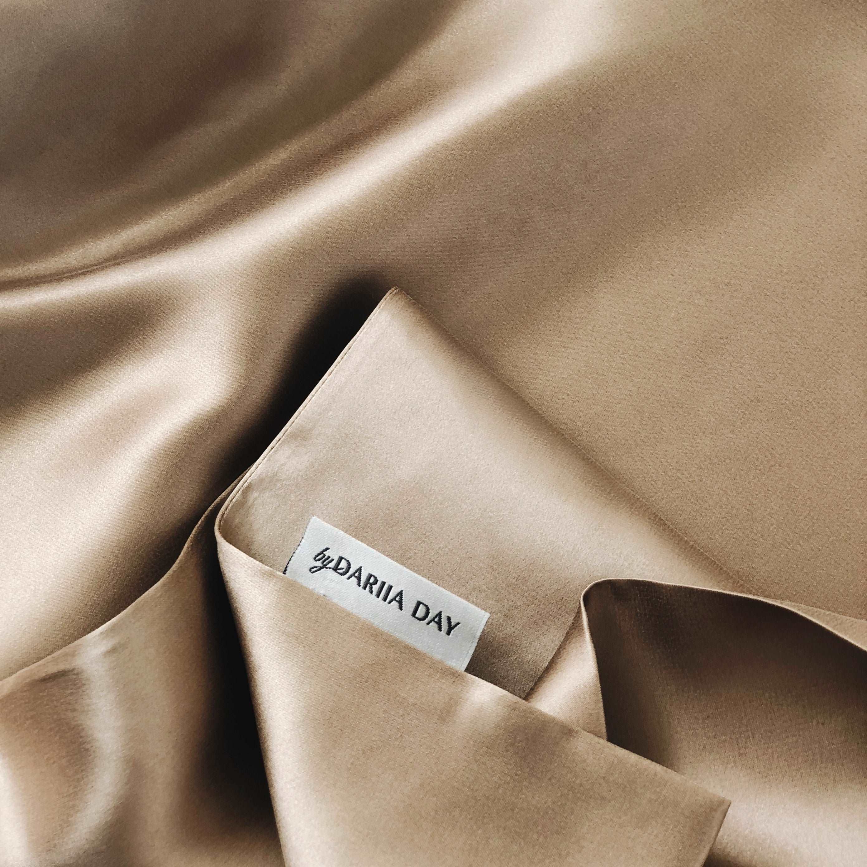 Close-up of beige silk pillowcase by Dariia Day, highlighting the softness and premium silk fabric detail.