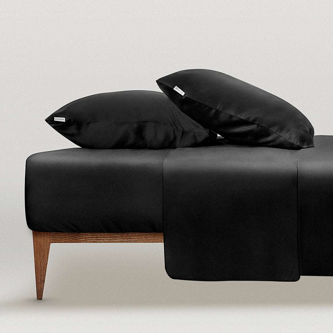 Luxurious black silk pillowcases on a minimalist bed setup, showcasing the softness and elegance of by Dariia Day products.