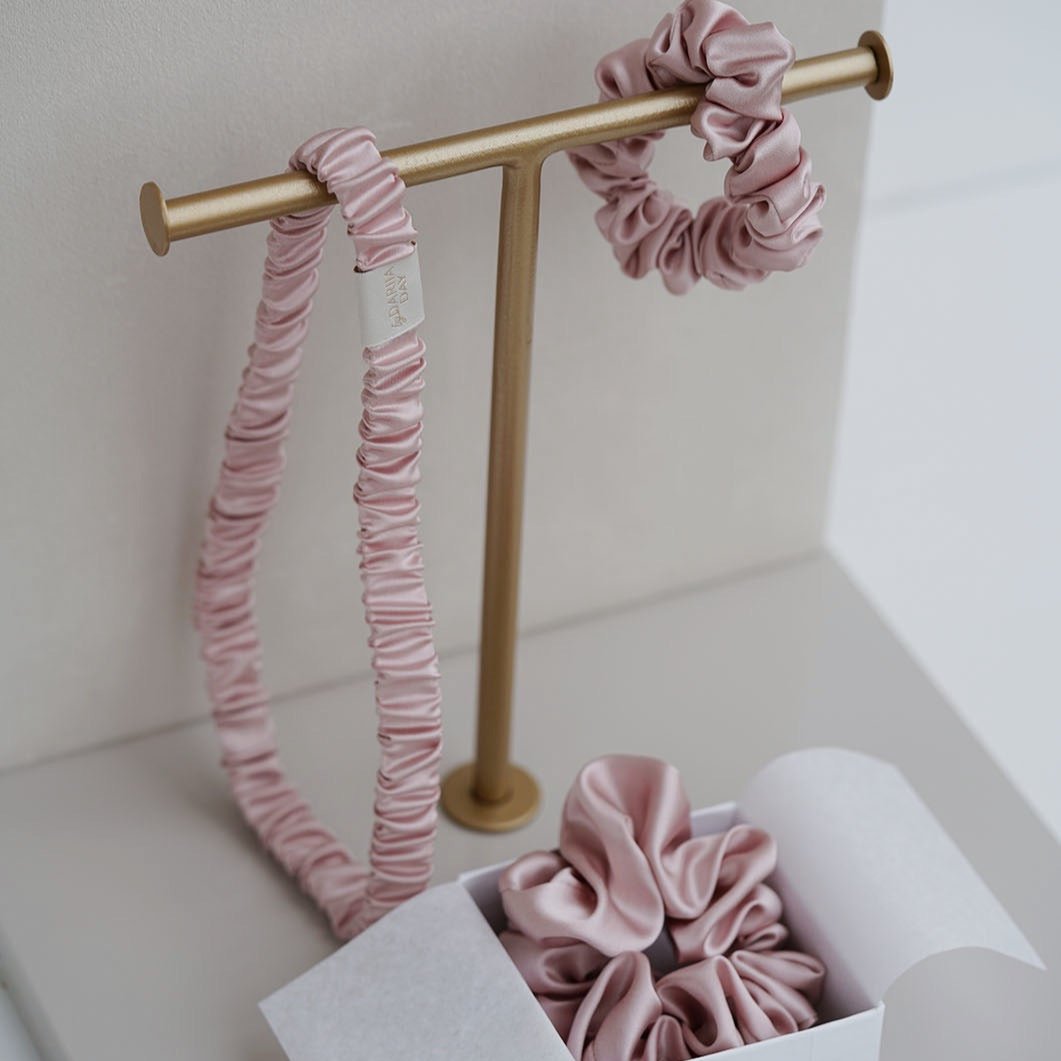 Elegant display of blush pink silk headband and scrunchie by Dariia Day, perfect for adding a touch of luxury to any hair care routine