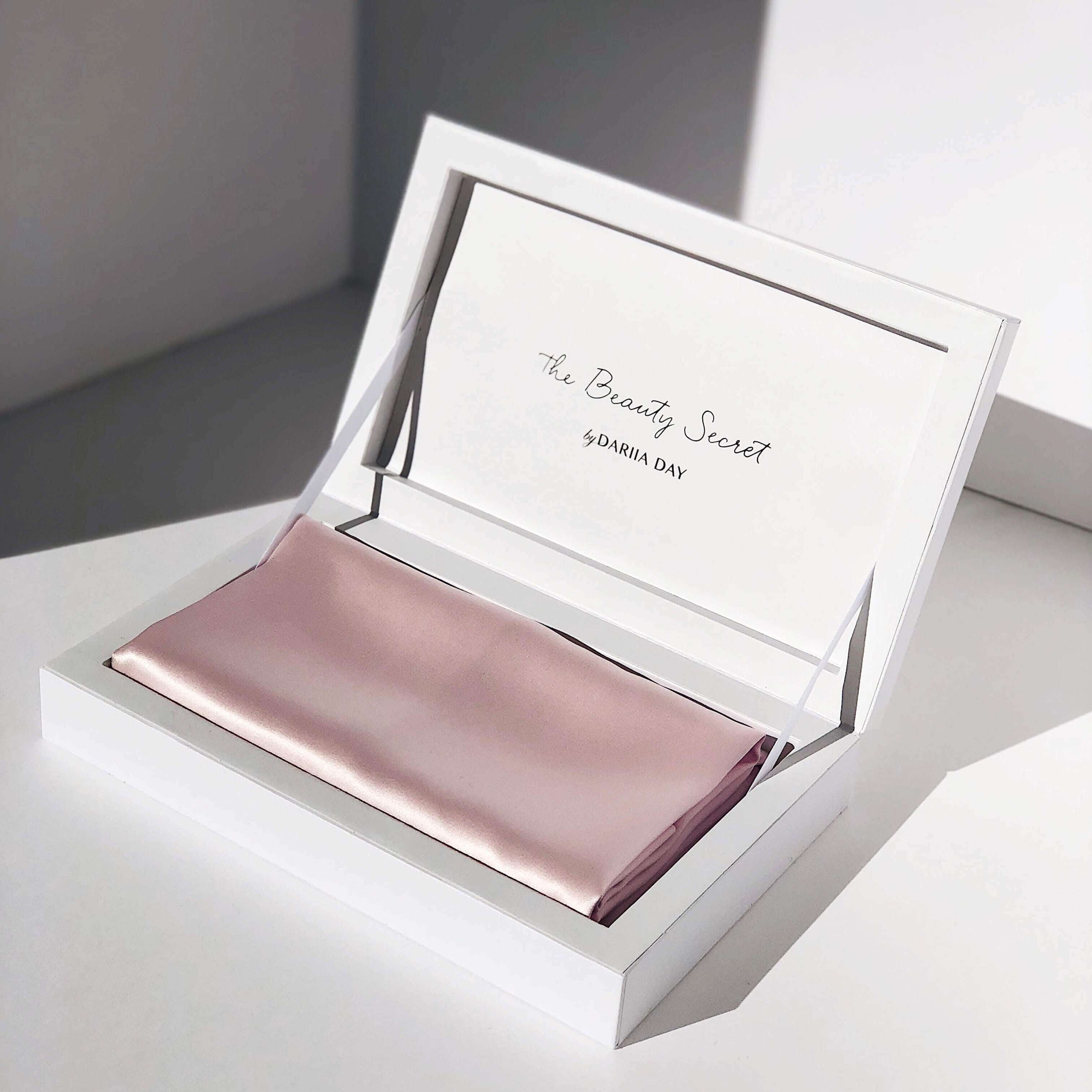 Close-up of a blush pink silk pillowcase in luxury packaging by Dariia Day.