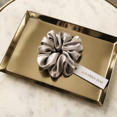 Grey silk scrunchie by Dariia Day, elegantly displayed on a gold tray, crafted from premium mulberry silk.