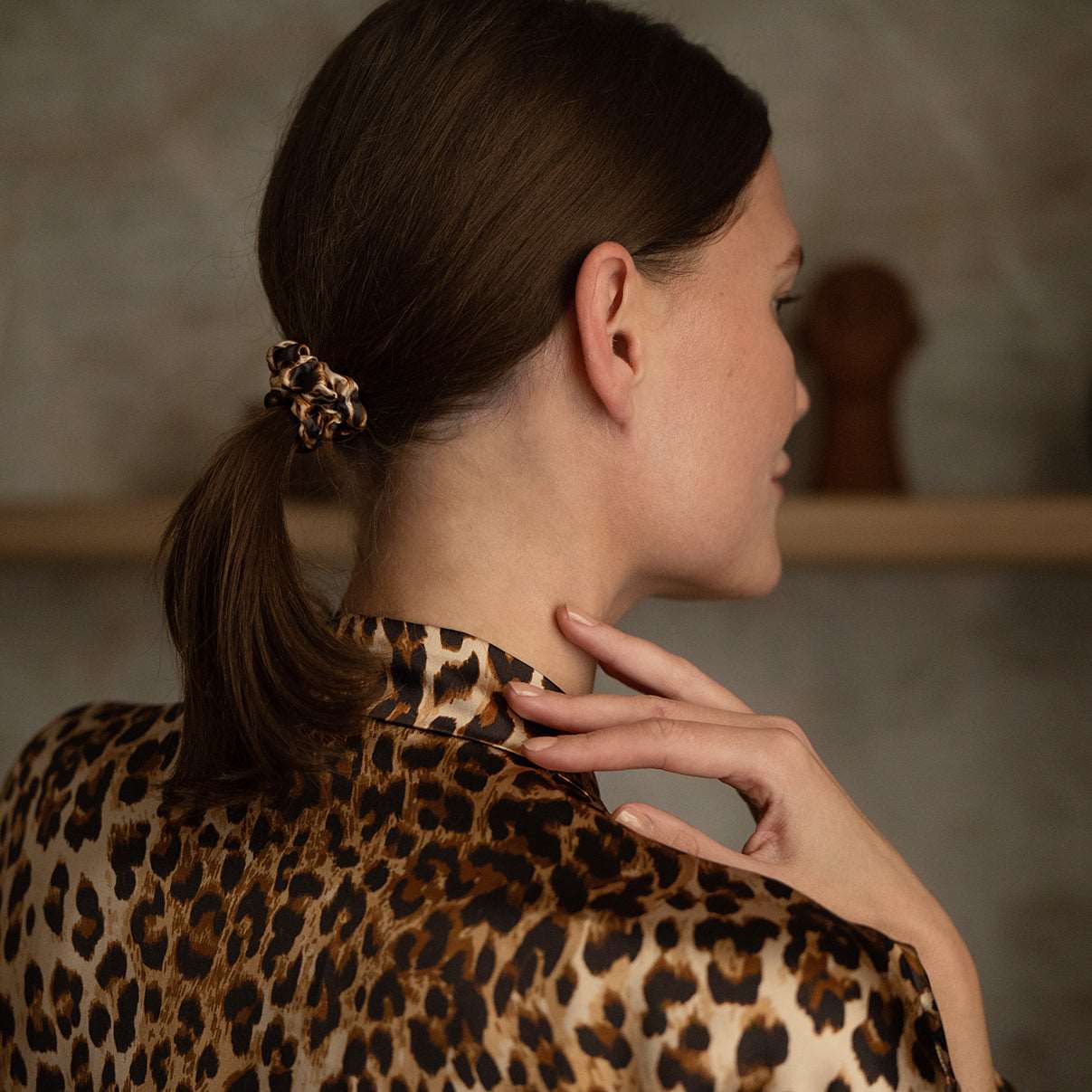 Back view of a woman wearing a leopard-print XS silk scrunchie and matching robe from the Daria Day Leopard collection, showcasing elegance and style.