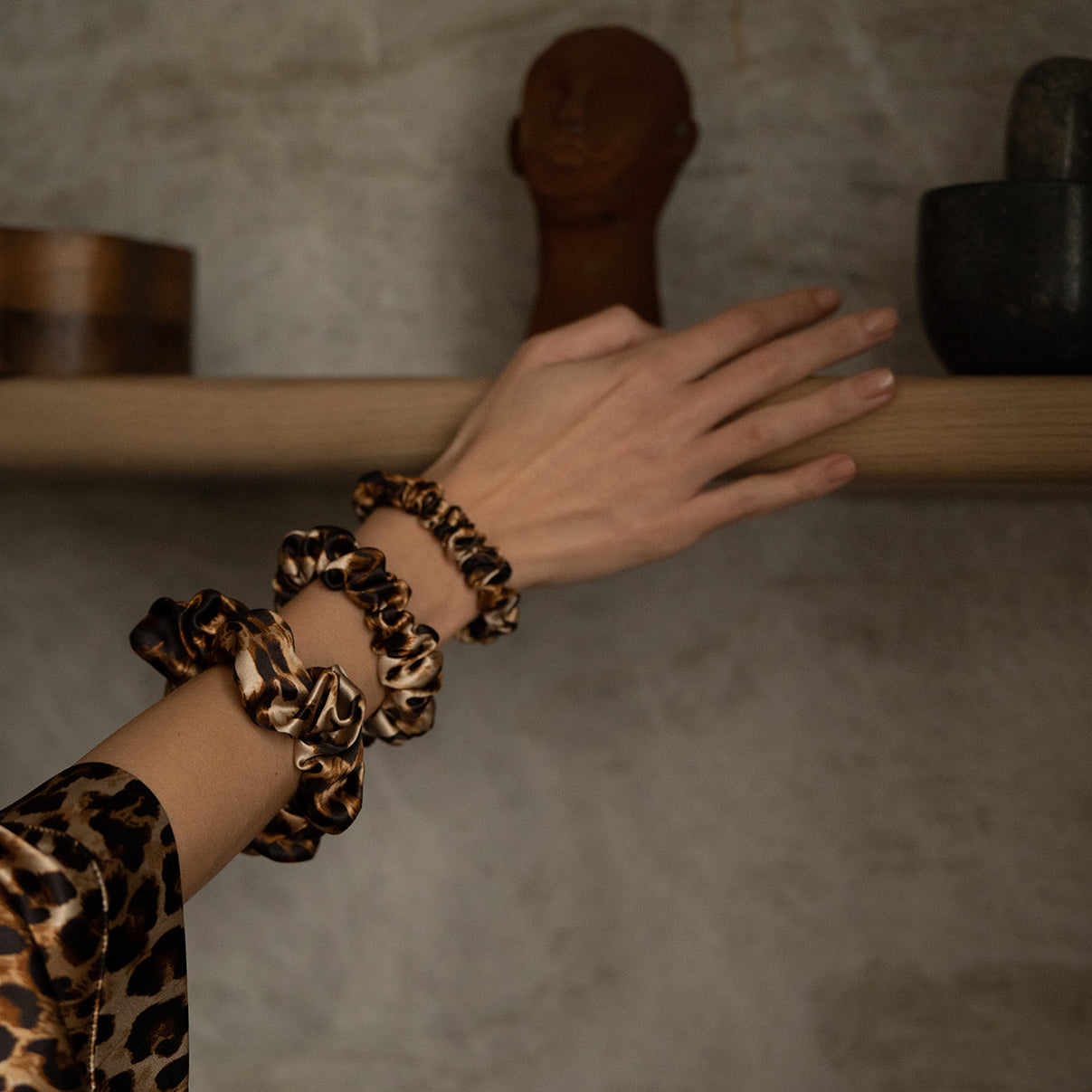 Close-up of a woman's hand adorned with leopard-print silk scrunchies from the Daria Day Leopard collection, showcasing luxury and attention to detail.