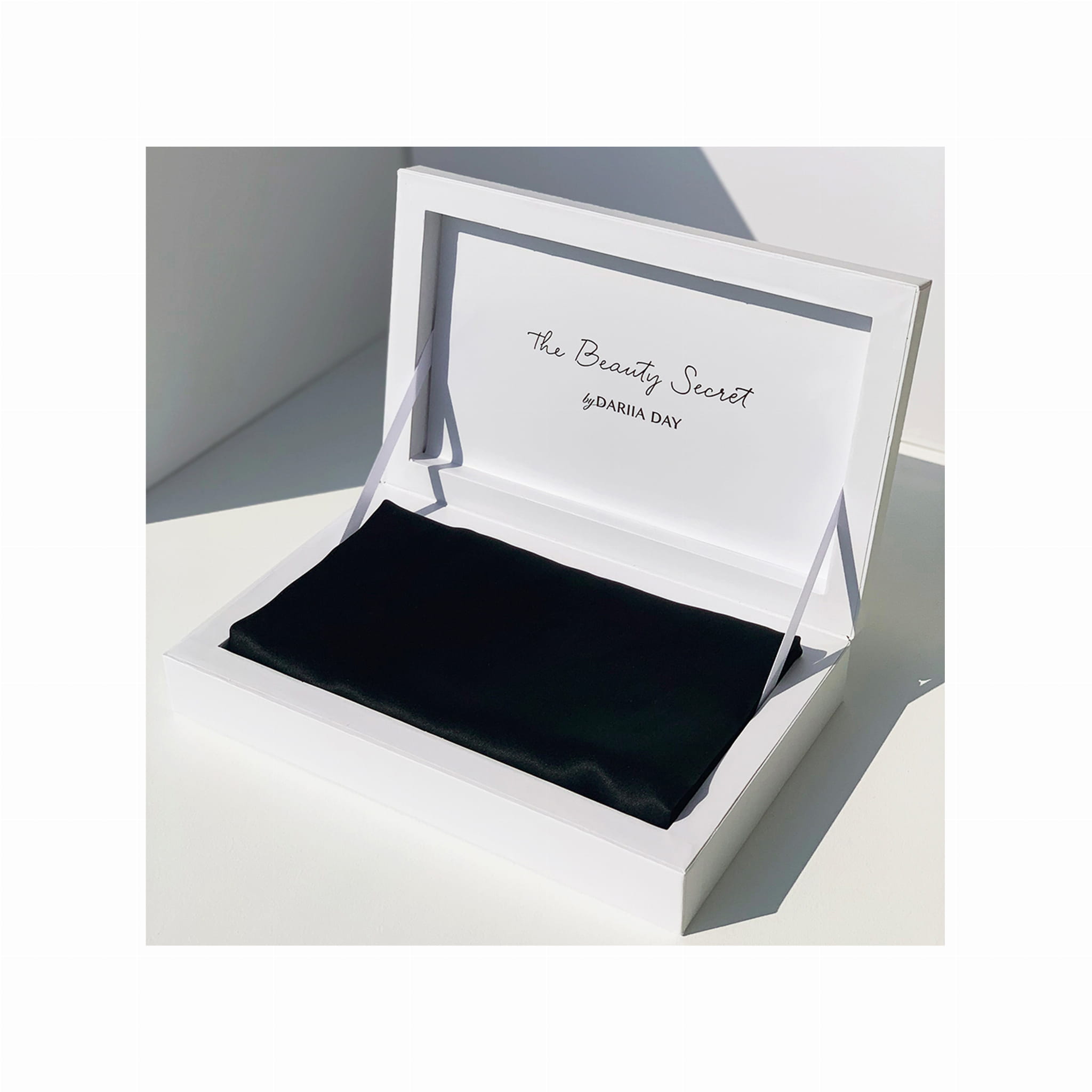 Black silk pillowcase elegantly displayed in a white box with 'The Beauty Secret by Dariia Day' inscription inside the lid.