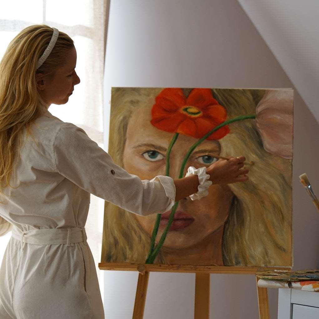 Female artist wearing by Dariia Day Powder White Silk Headband and Scrunchie while painting, showcasing luxurious hair protection with mulberry silk.