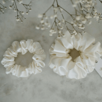 Close-up of by Dariia Day Powder White Silk Headband on a marble surface, designed for stylish and gentle hair care.