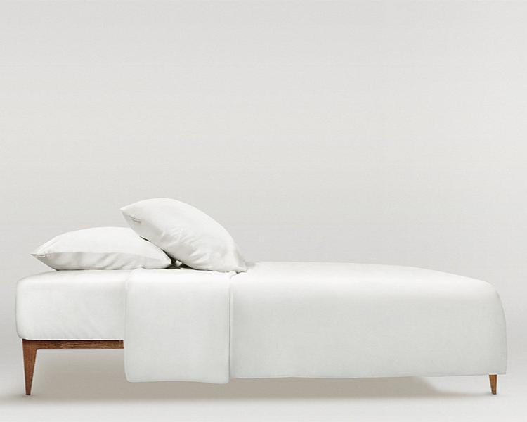 White Minimalist bed styled with a powder white silk bedding set, including pillowcases and a duvet cover.