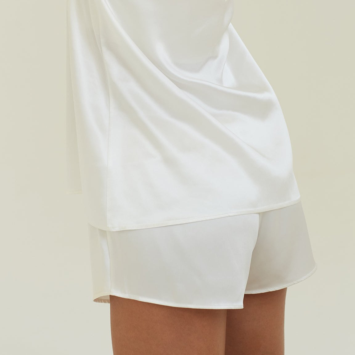 Model wearing powder white silk shorts with matching top by Dariia Day, showcasing elegant sleepwear.