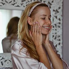 A woman in a silk robe smiles while wearing the luxurious blush pink silk headband by Dariia Day