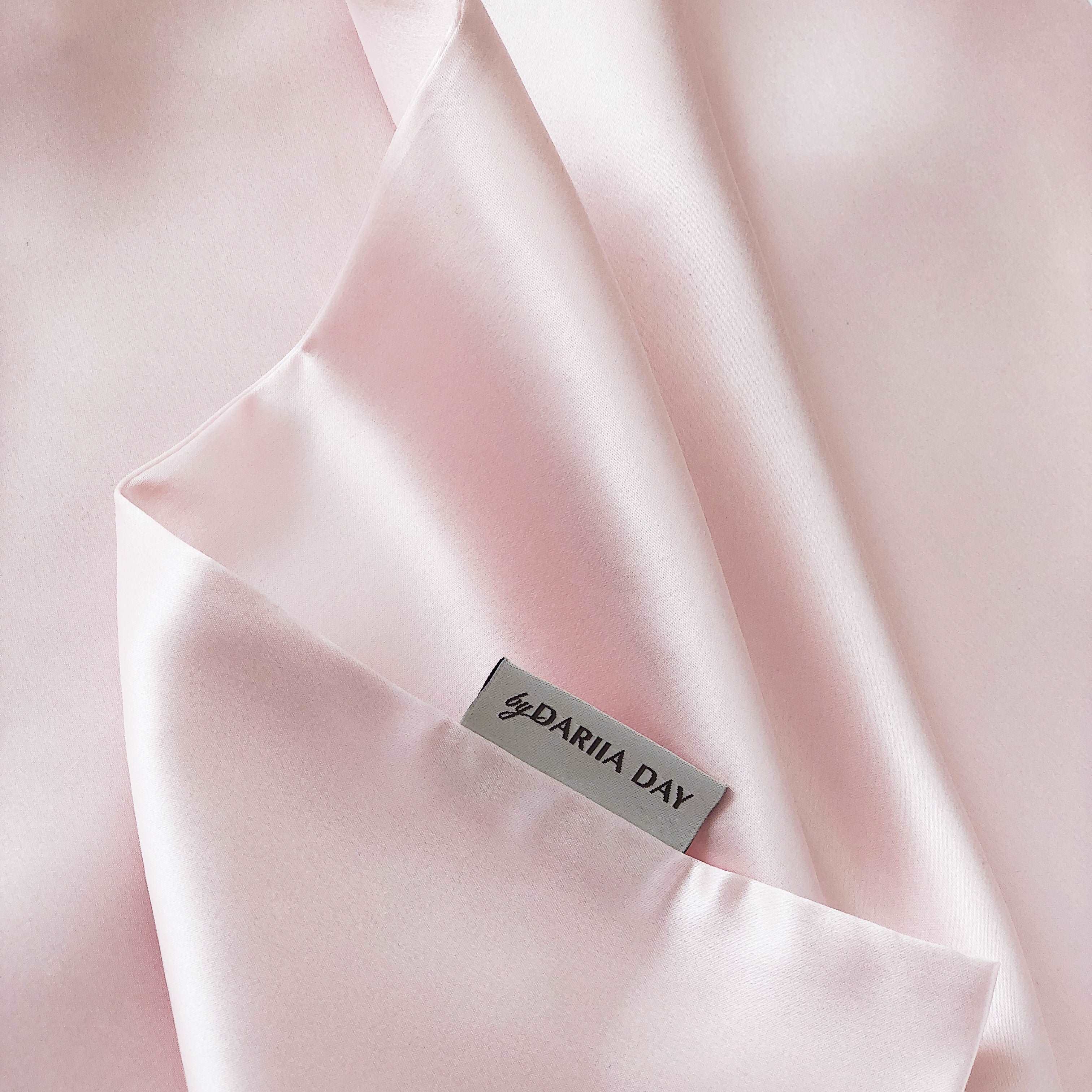 Close-up of a pink silk pillowcase by Dariia Day, showcasing smooth, soft, and luxurious fabric.