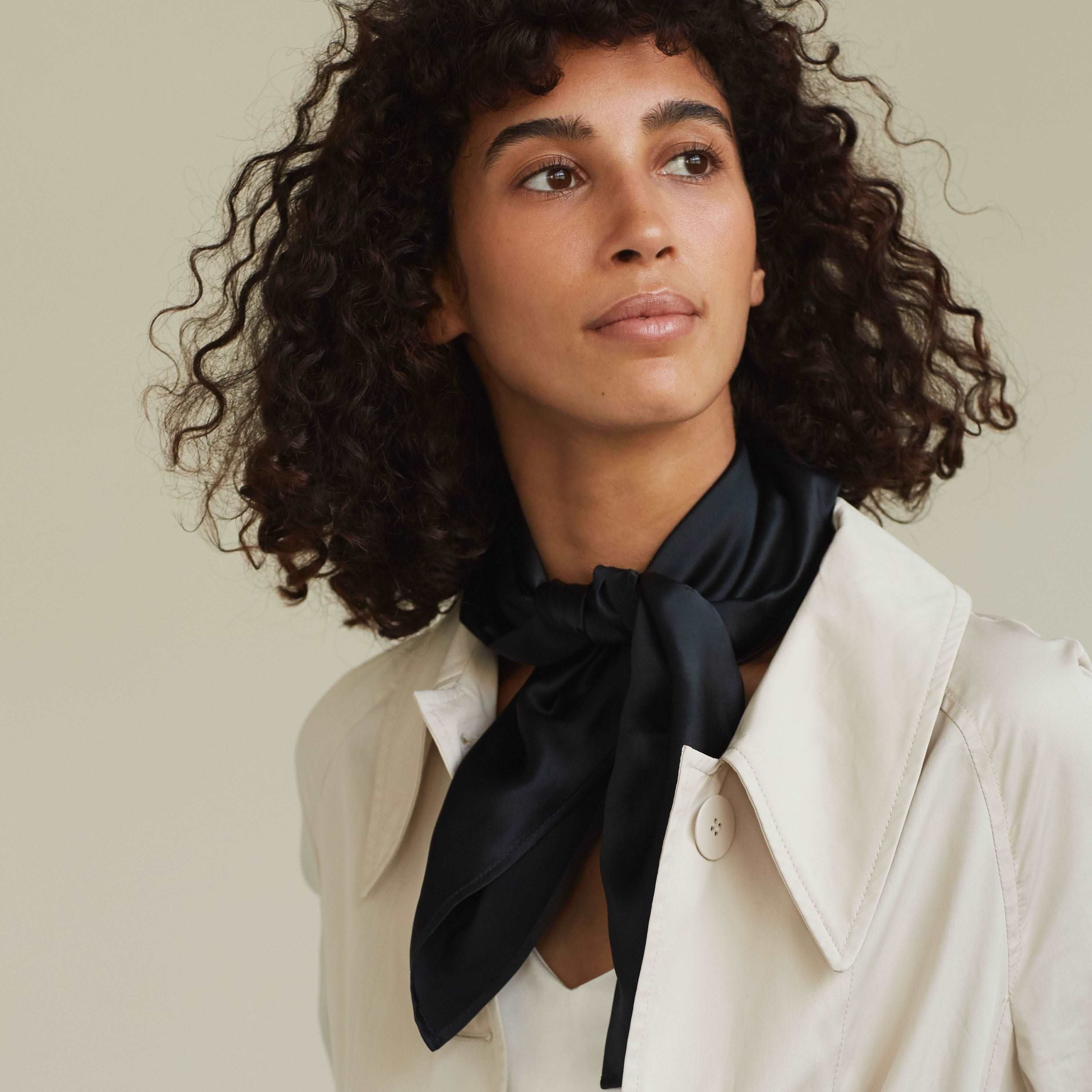 Black A woman wearing a black silk scarf by Dariia Day, tied elegantly around her neck, minimal and chic style