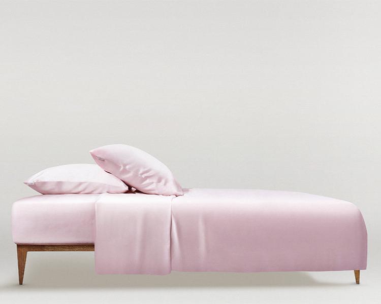 Elegant blush pink silk bed with matching pillowcases and duvet cover, minimalist design