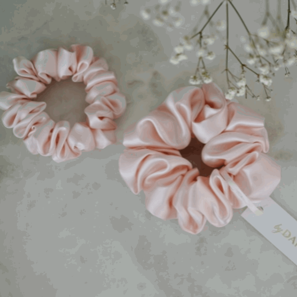 Blush pink silk scrunchie set by Dariia Day on a marble surface.