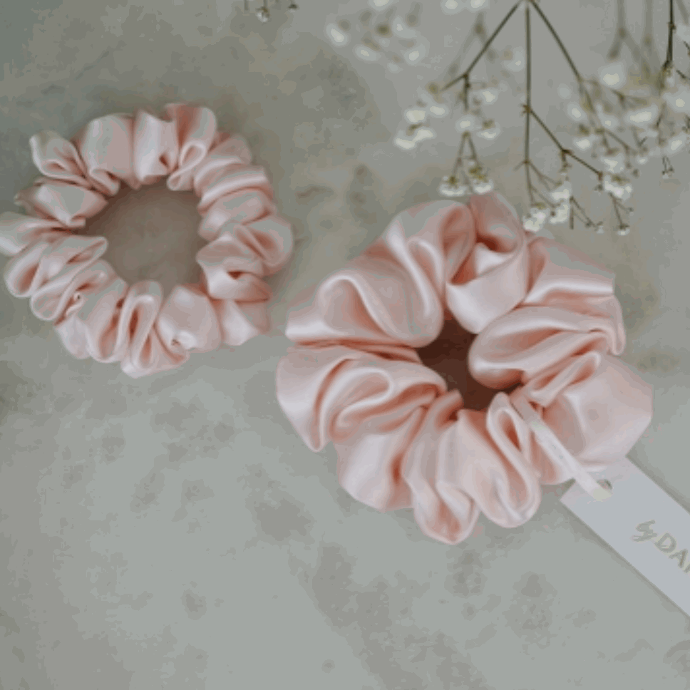 Blush pink silk scrunchie set by Dariia Day on a marble surface.