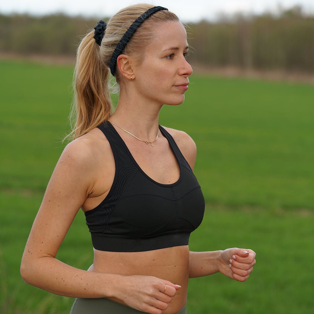 Woman wearing a Midnight Black silk headband by Dariia Day during an outdoor workout, showcasing its versatility for activewear.