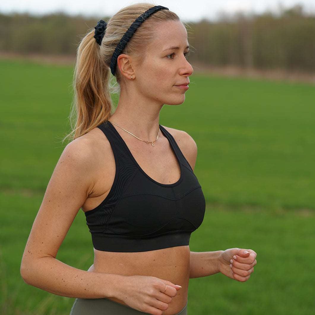 Woman wearing a Midnight Black silk headband by Dariia Day during an outdoor workout, showcasing its versatility for activewear.