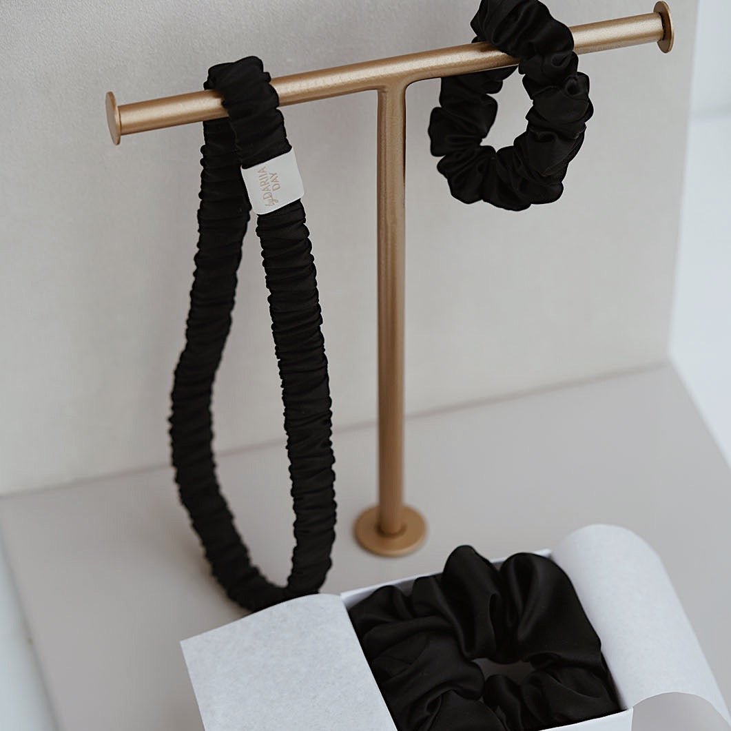 Midnight Black silk scrunchie and headband set by Dariia Day in a gift box, with the headband displayed on a minimalist golden stand.