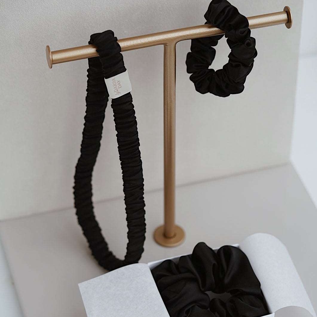 Midnight Black silk scrunchie and headband set by Dariia Day in a gift box, with the headband displayed on a minimalist golden stand.