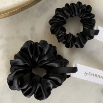 Black Two Midnight Black silk scrunchies by Dariia Day on a marble surface with branded tags.