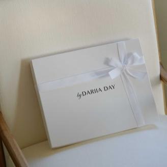 Dariia Day Bridal Luxury Set gift box with ribbon placed on a white upholstered chair, ready for gifting.