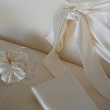 Close-up of Dariia Day Bridal Luxury Set's scrunchie, silk robe with bow detail, and accessories for a luxury bridal experience