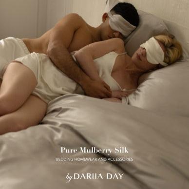 Couple wearing silk sleepwear and eye masks from the Dariia Day wedding gift set, sleeping together on luxury bedding.