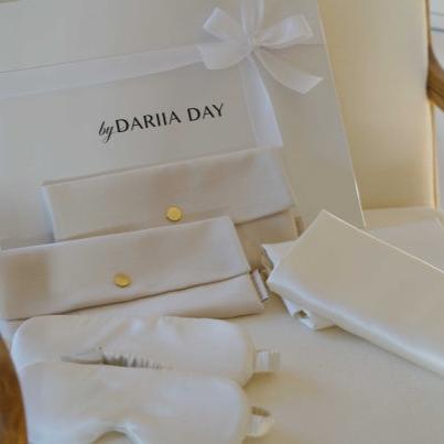 Close-up of Dariia Day silk wedding gift set with white pouches, silk eye masks, and pillowcases displayed in a gift box.