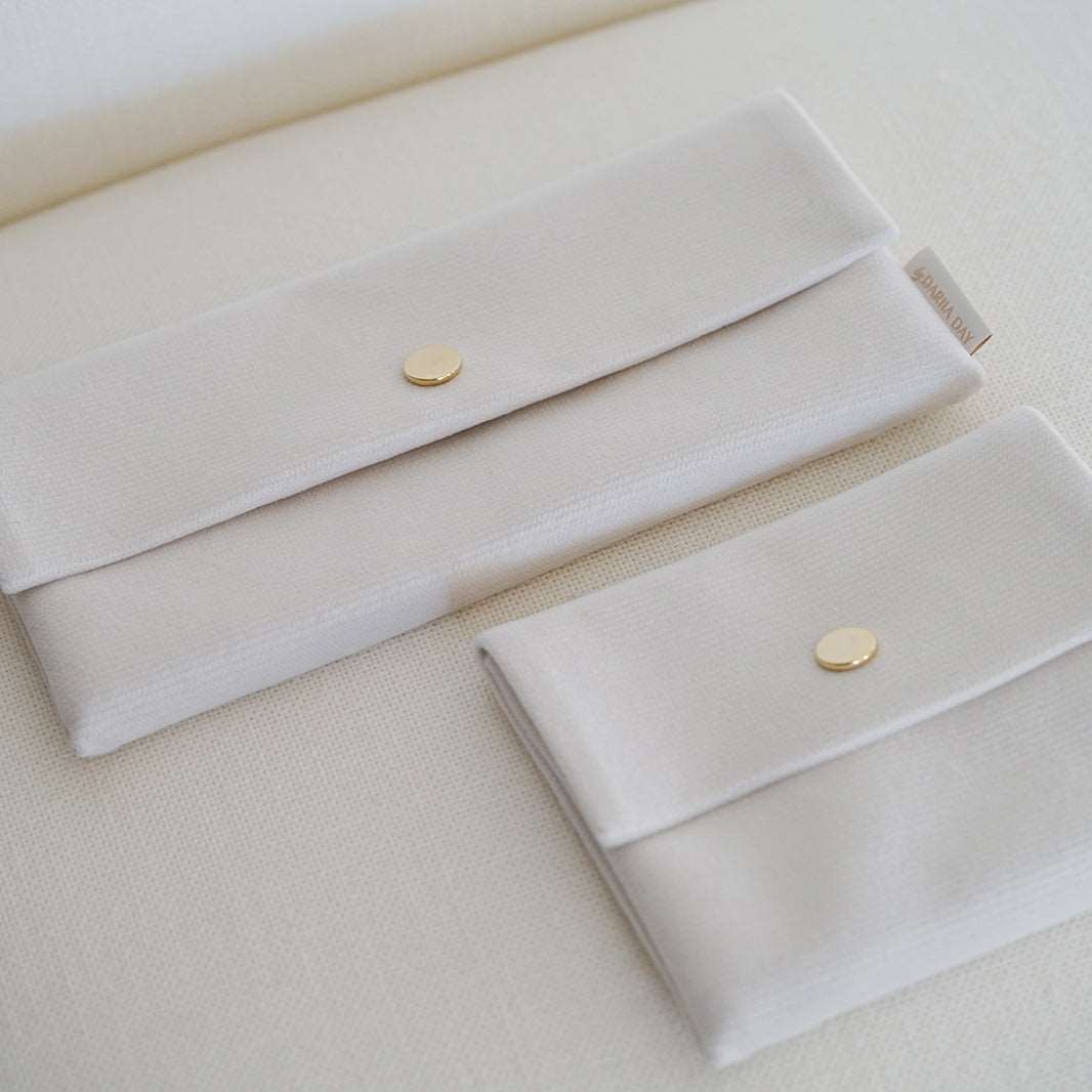 Dariia Day White Vanilla Velvet Pouches in two different sizes, side by side on a beige surface