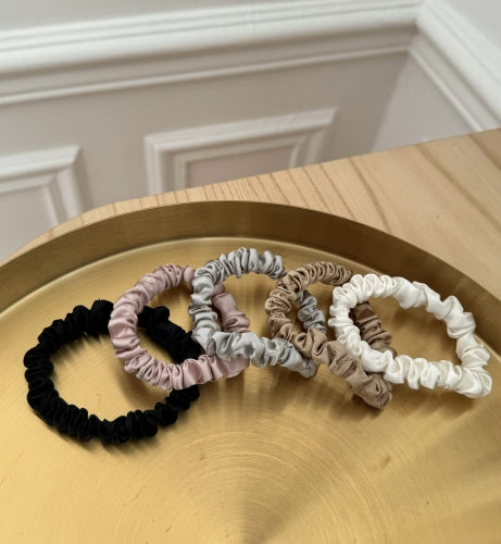 Set of 5 XS silk scrunchies in Midnight Black, Pink Blush, Silver Grey, French Beige, and Powder White by Dariia Day, arranged on a gold tray.