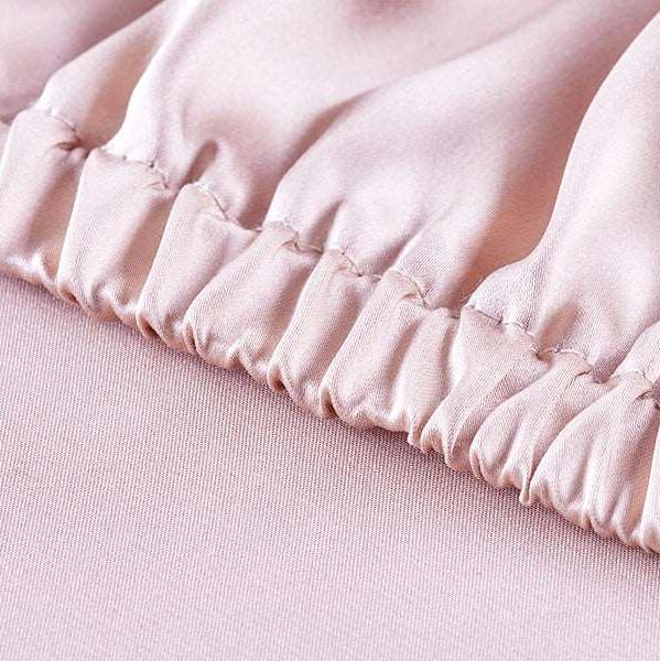 Close-up of smooth mulberry silk fabric in blush pink fitted sheet.