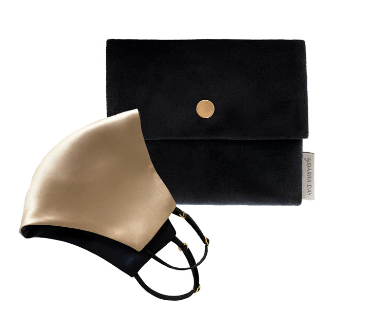 Beige French beige silk face mask with black adjustable straps, displayed alongside a black pouch with a gold button closure.