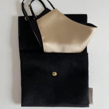 French beige silk face mask with a black pouch, folded and displayed elegantly against a white background