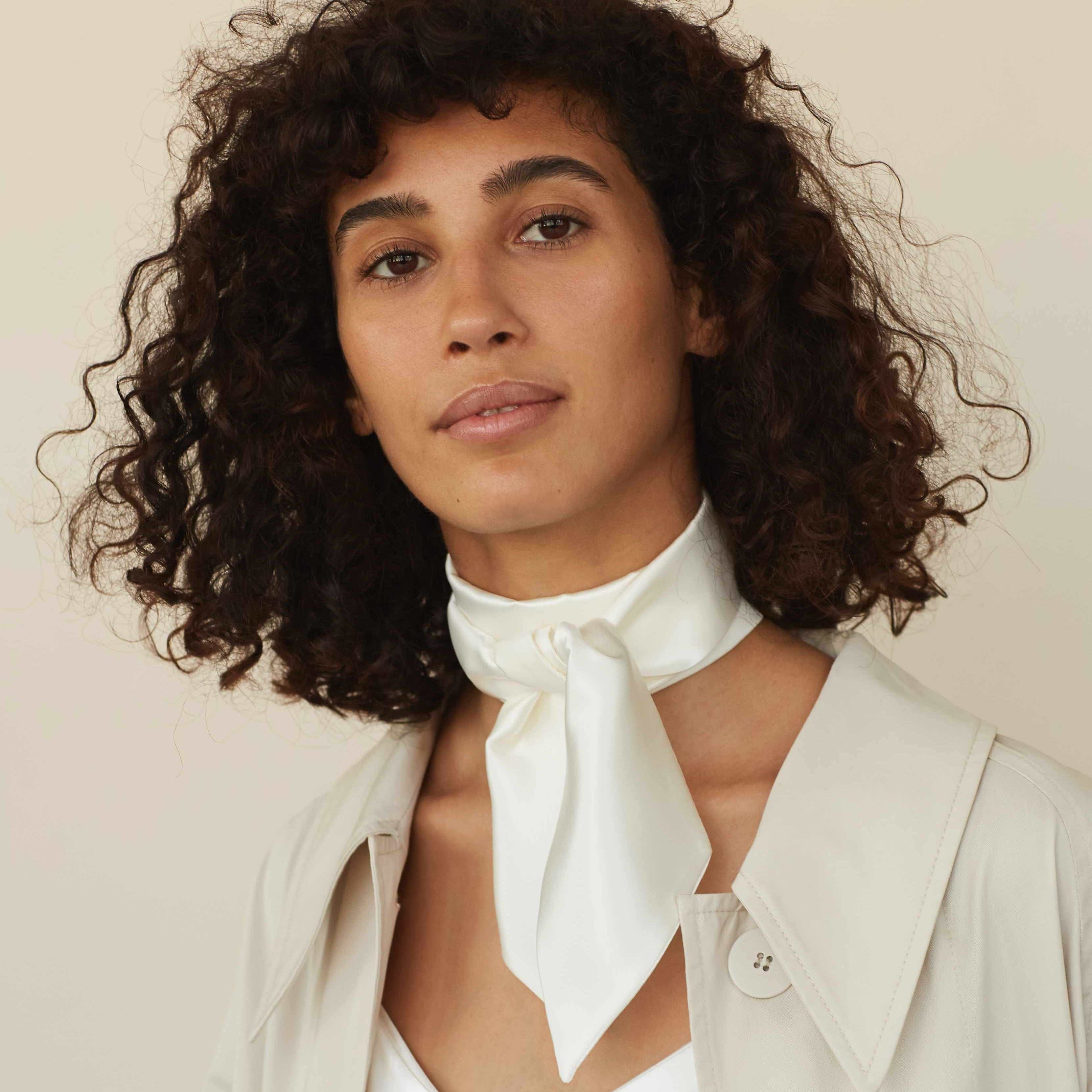 Model wearing a powder white silk scarf tied around the neck by Dariia Day