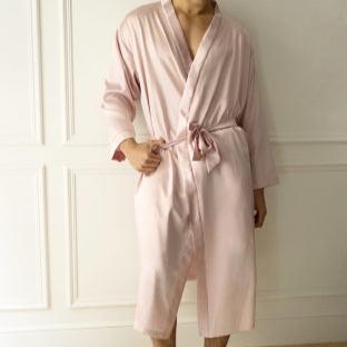 Man wearing a light pink silk robe and matching shorts by Dariia Day, standing by a window in a modern room.